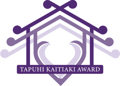 The logo of the Tapuhi Kaitiaki awards. It is a stylised outline of a Māori wharenui with a heart embedded in the middle. It's in shades of purple. The Base of the whare is the words "tapuhi kaitiaki awards".. 